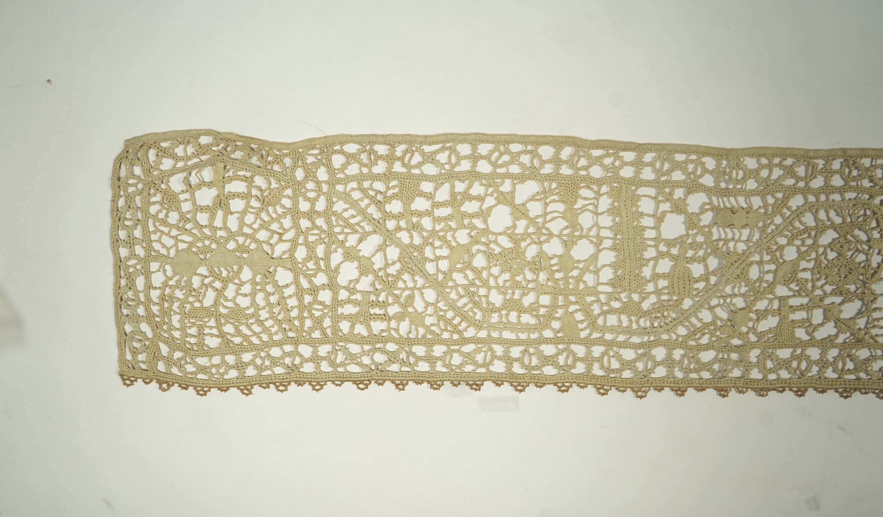 A length of late 16th early 17th century Venetian Reticella needle lace. Possibly cut from a wider panel or the edge to an Ecclesiastical robe or a furnishing lace. Designed with figures, worked in button hole stitch. 17
